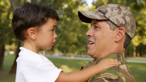 papá militar feliz sosteniendo a su pequeño hijo en brazos