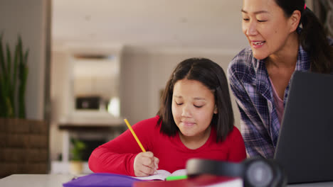 video of happy asian mother and daughter doing homework together