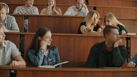 The-group-of-cheerful-happy-students-sitting-in-a-lecture-hall-before-lesson.-The-group-of-cheerful-students-sitting-in-a-lecture-hall-before-lesson.