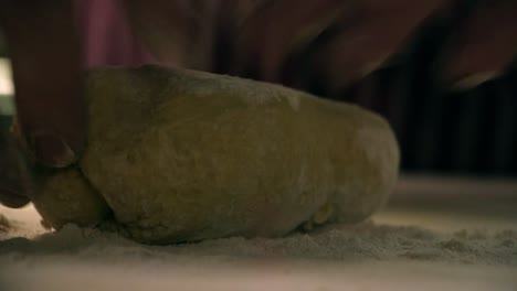 Close-up-flour-raining-on-pasta-dough-and-hands-working-the-ball-of-dough