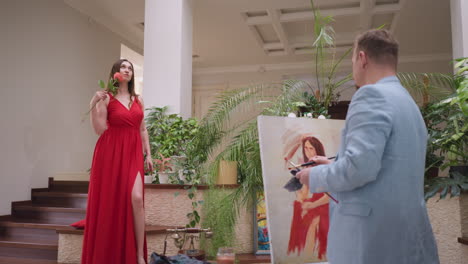 el artista produce una obra maestra pintando a una mujer. la pose de modelo y la delicada rosa en la mano proporcionan inspiración para los esfuerzos creativos del artista. el ambiente del arte