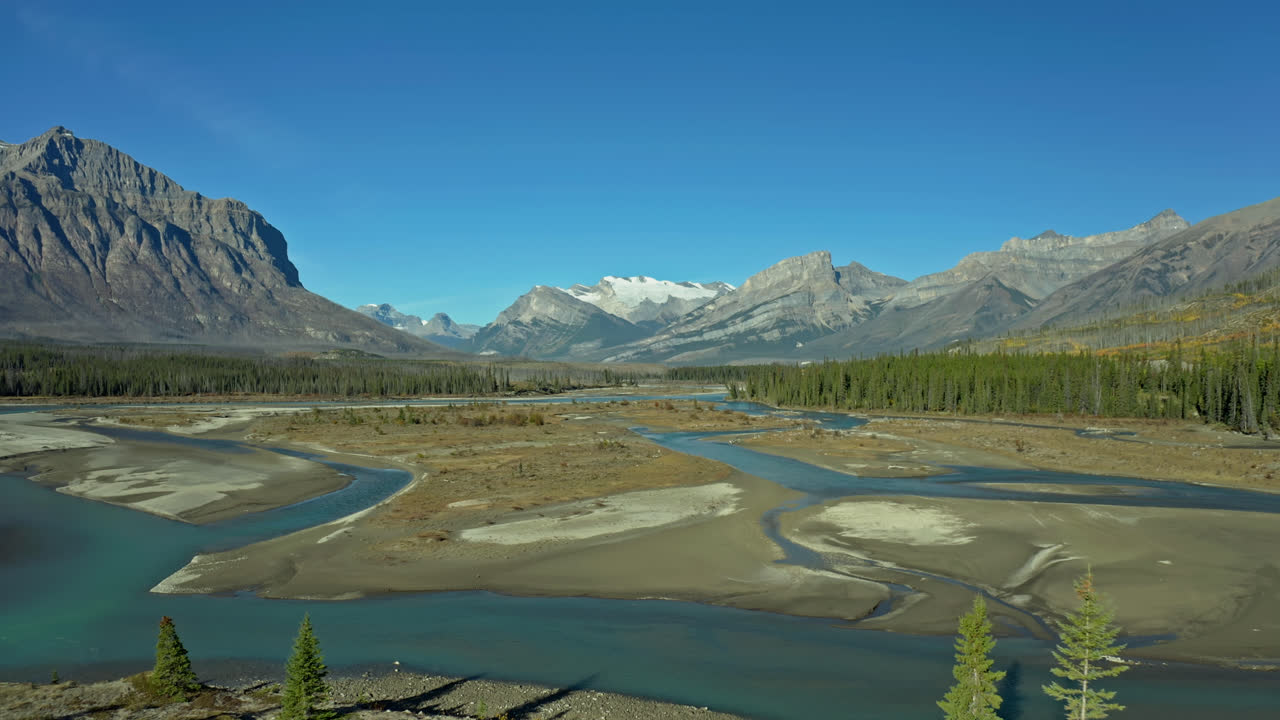Lone hiker by mountains, streams and forest in Alberta, Canada, wide aerial