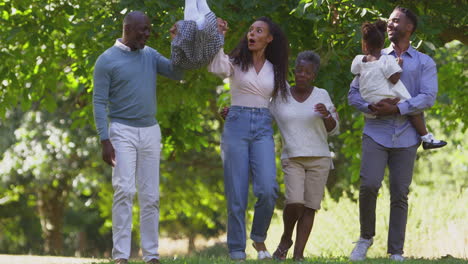 Mehrgenerationenfamilie-Genießt-Gemeinsam-Einen-Spaziergang-Auf-Dem-Land-Und-Schaukelt-Ihre-Enkelin