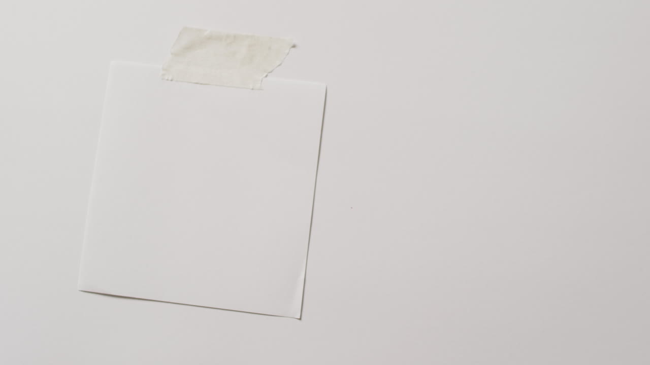 video de un primer plano de una nota de nota blanca con espacio de copia pegado a un fondo blanco