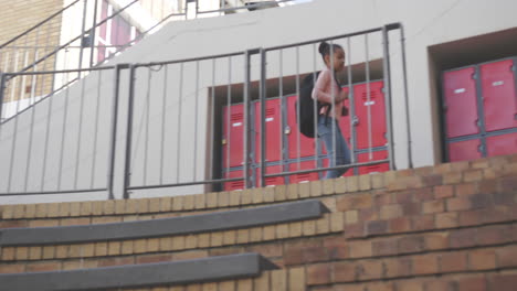 walking down stairs, african american girl with backpack heading to school lockers