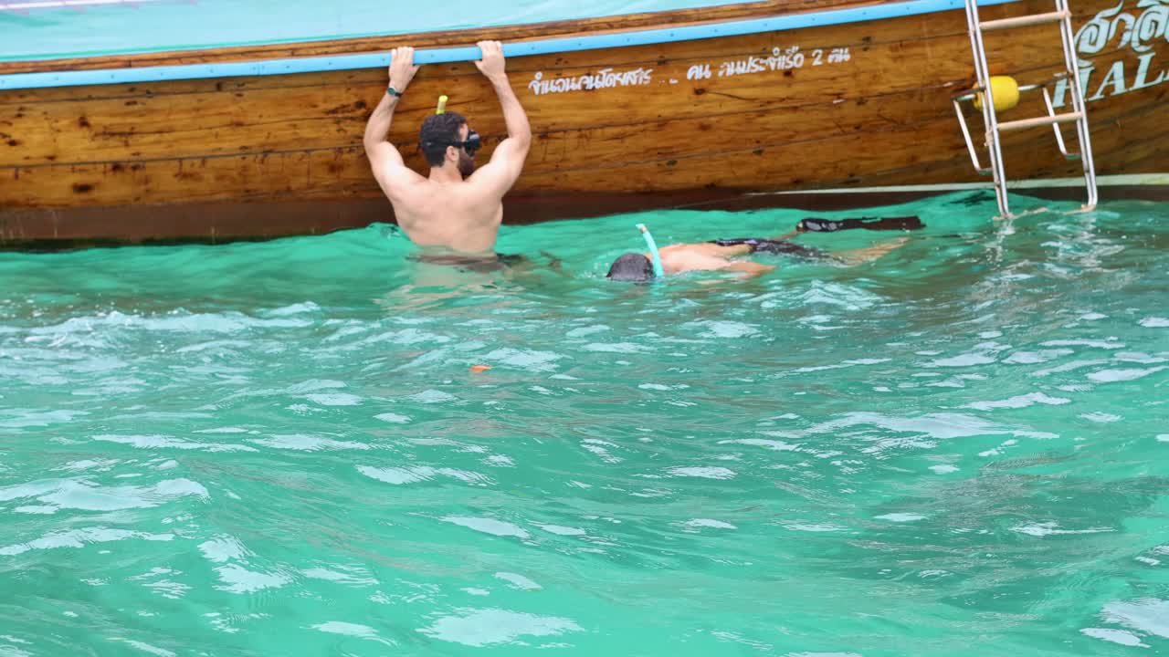 personas nadando cerca de un barco de cola larga