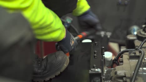 mechanic tightens a nut on a bolt in a vice alongside colleague