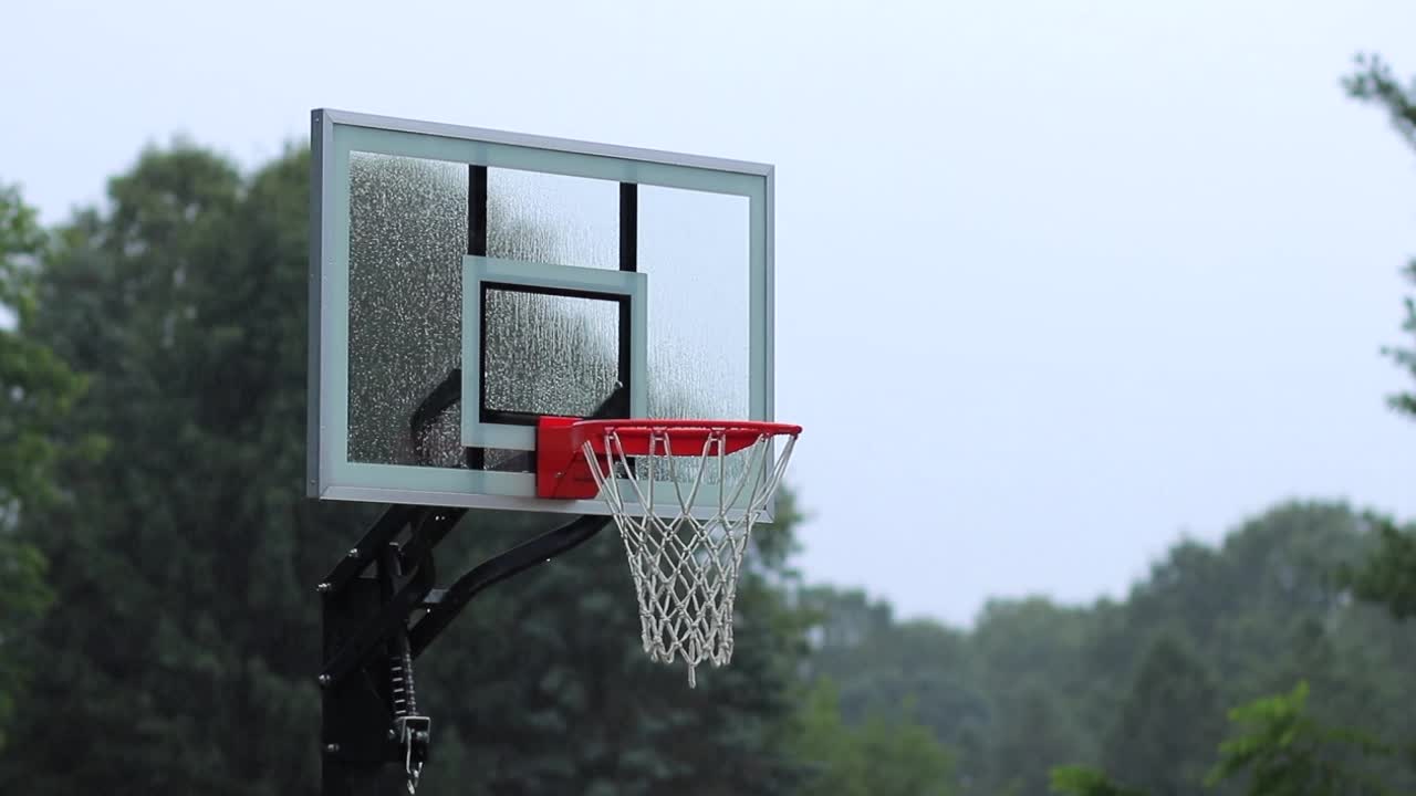 red de baloncesto al aire libre sin usar con tablero de vidrio en lluvia brumosa