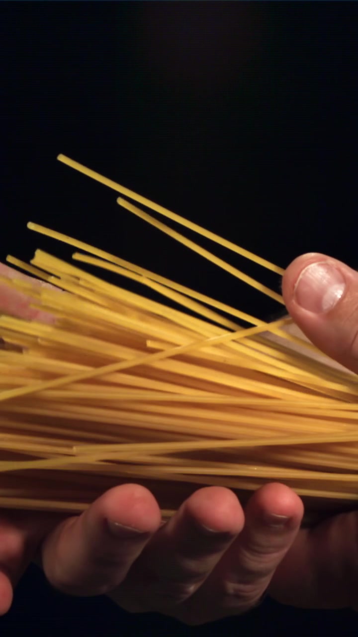 Mani al rallentatore che lasciano cadere spaghetti secchi