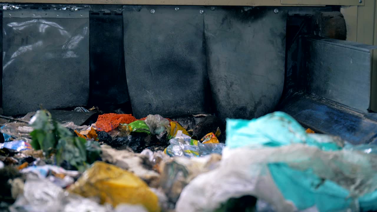 un trabajador clasifica la basura en una línea, de cerca. un trabajador de la fábrica saca papeles de un transportador con basura.