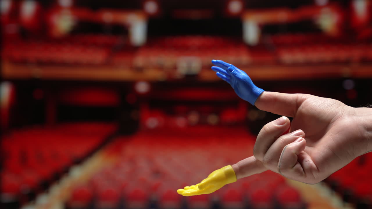 un pequeño títere de mano aplaudiendo en un teatro vacío