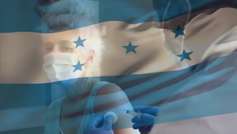 Animación-De-La-Bandera-De-Honduras-Ondeando-Sobre-Un-Médico-Con-Mascarilla-Y-Vacunando-A-Una-Mujer-Mayor