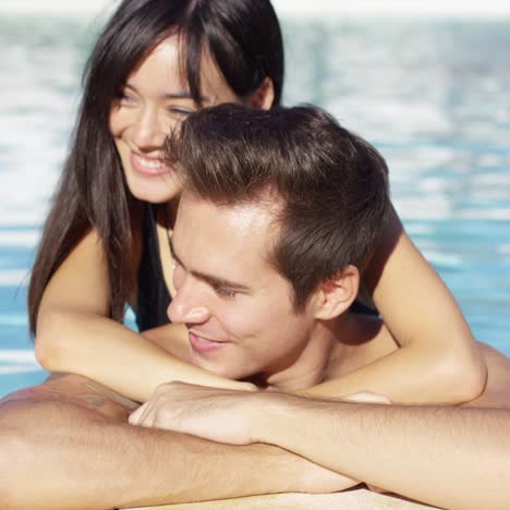 beautiful woman cuddles with her boyfriend in pool