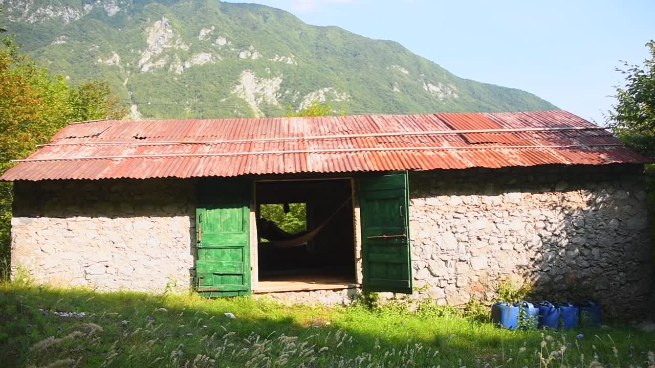 mujer joven relajándose en una hamaca dentro de una cabaña de montaña con paredes de piedra