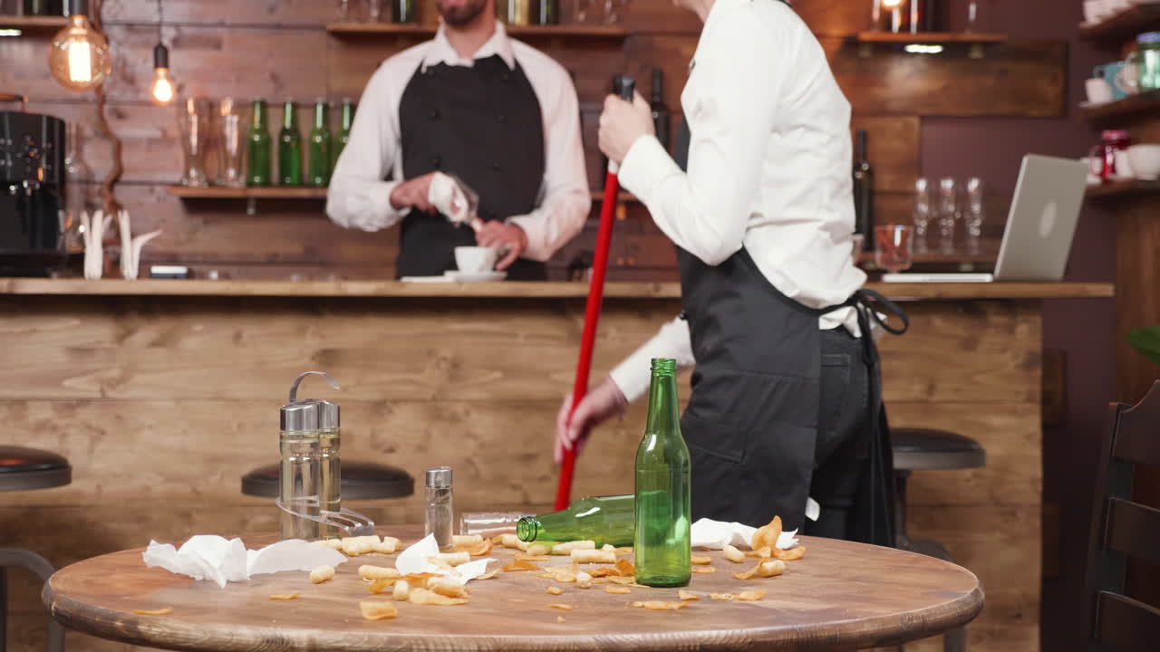 Bartenders Cleaning a Messy Table in a Bar