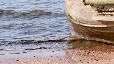 waves gently lap against a beached boat