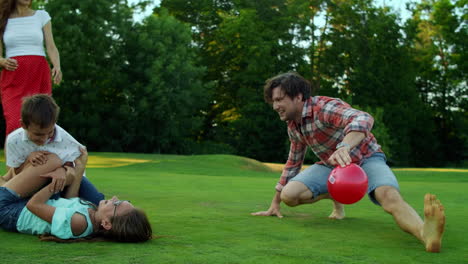 girl lying on grass with ball in field. young family playing with ball in meadow