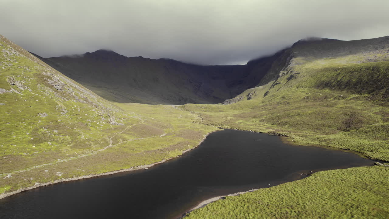 잔디로 뒤덮인 산 안에 호수가 있는 작은 강의 아름다운 공중과 돌 구름으로 뒤덮인 산맥이 뒤에 놓여 있습니다-1