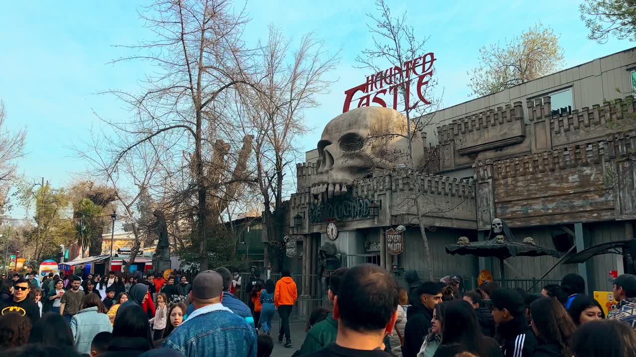 Panoramic view establishing the haunted castle totally full of people, Fantasilandia amusement park in Santiago, Chile.