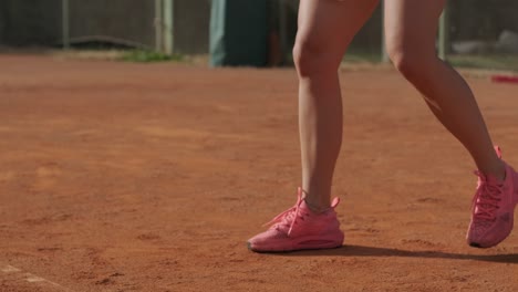 a young woman practicing tennis on an outdoor court with a coach. the coach provides guidance as the player works on her technique, perfecting her strokes in an athletic training session.