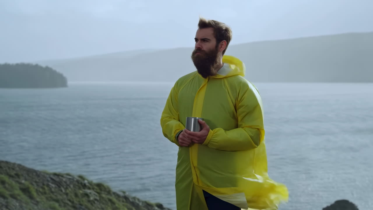 Mann mit Regenmantel, der auf einen See blickt