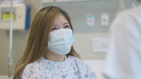 close up shot of a middle-aged female patient with face mask talking happily to a nurse