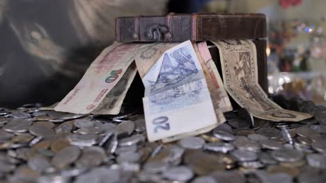 decorative chest with old bills on pile of antique coins, selective focus