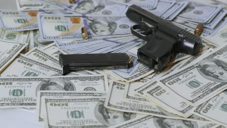 handgun, magazine, and bullets placed on a pile of 100 us dollar bills. symbolic of crime, security, or financial risks. depicts themes of danger, law enforcement, or illegal activities