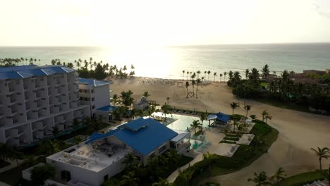 evening aerial of resort and ocean with golden sunset sky, orbit around cap cana juanillo beach dominican republic