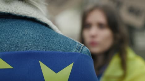 Man-and-woman-covered-with-EU-and-Ukraine-flags-standing-face-to-face-and-talking.