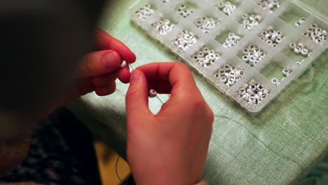 closeup of female threading beads on to a handmade bracelet, jewellery making arts and crafts