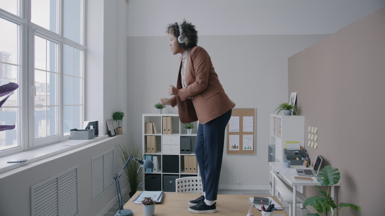 Happy Woman Dancing on Desk in Office