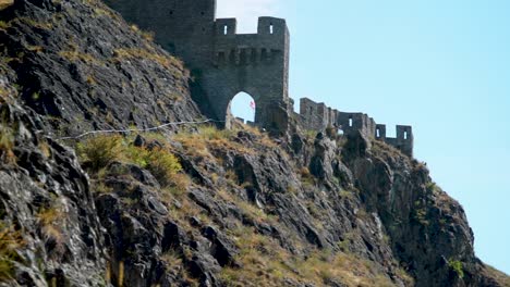 Truck reveal shot of medieval Chateau de Tourbillon castle wall in Swiss alps