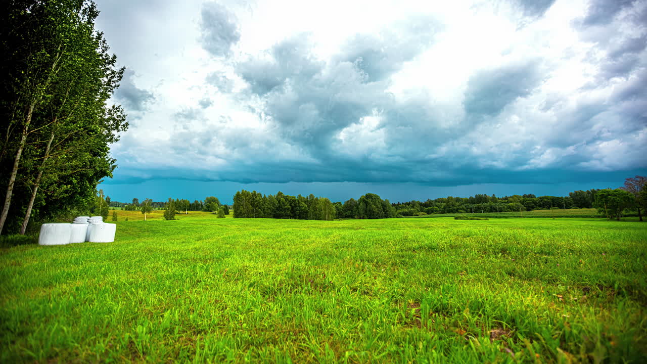 라트비아의 하늘을 가로질러 떠다니는 낮은 구름과 함께 시골의 녹색
