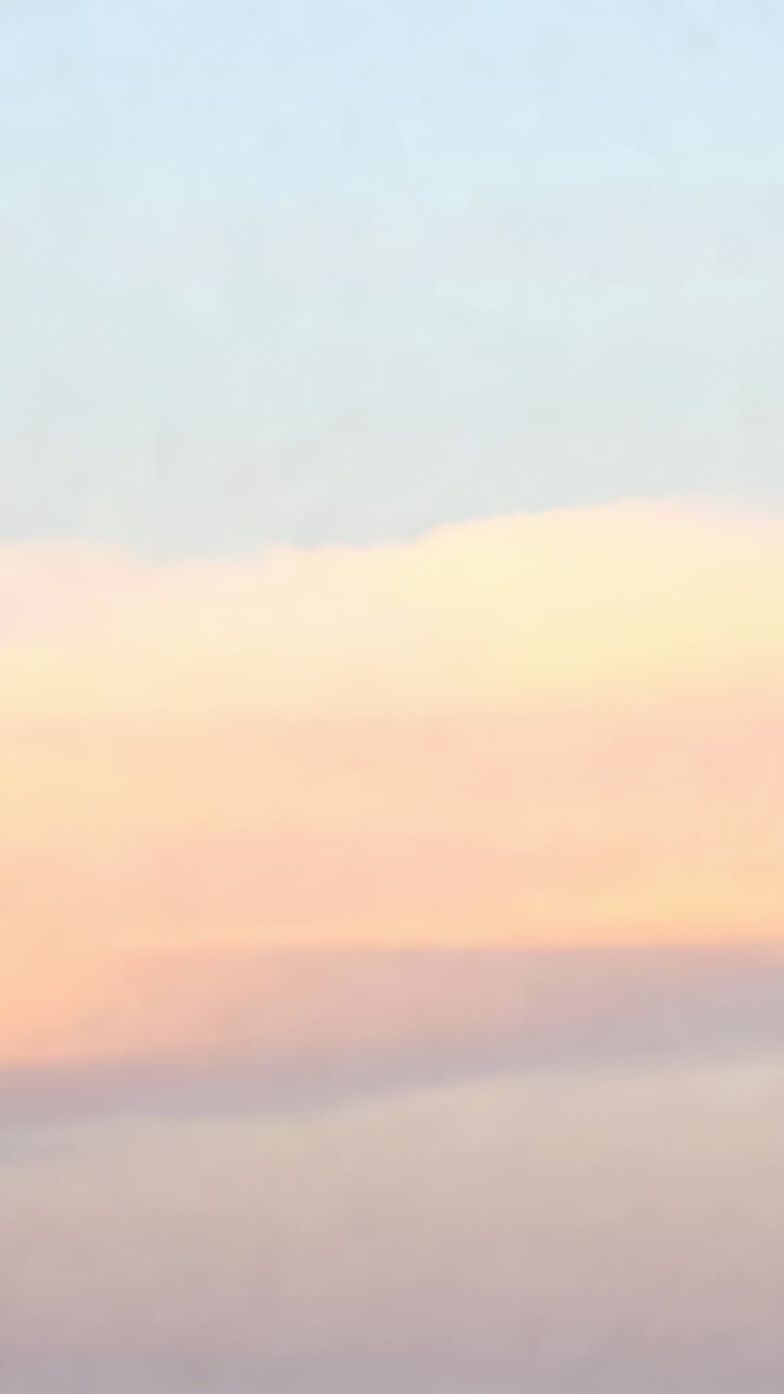 Vertical video: Drifting cloud bank and blue sky shifting warm orange, gray tones during sunset