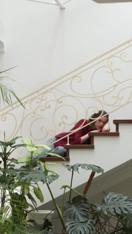 young woman with emotional breakdown lies on staircase. depressed lady suffers from mental health disorder at home. psychological treatment need