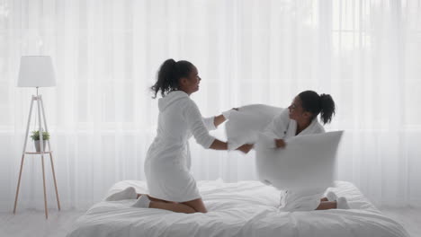 hermanas divirtiéndose luchando con almohadas en el dormitorio