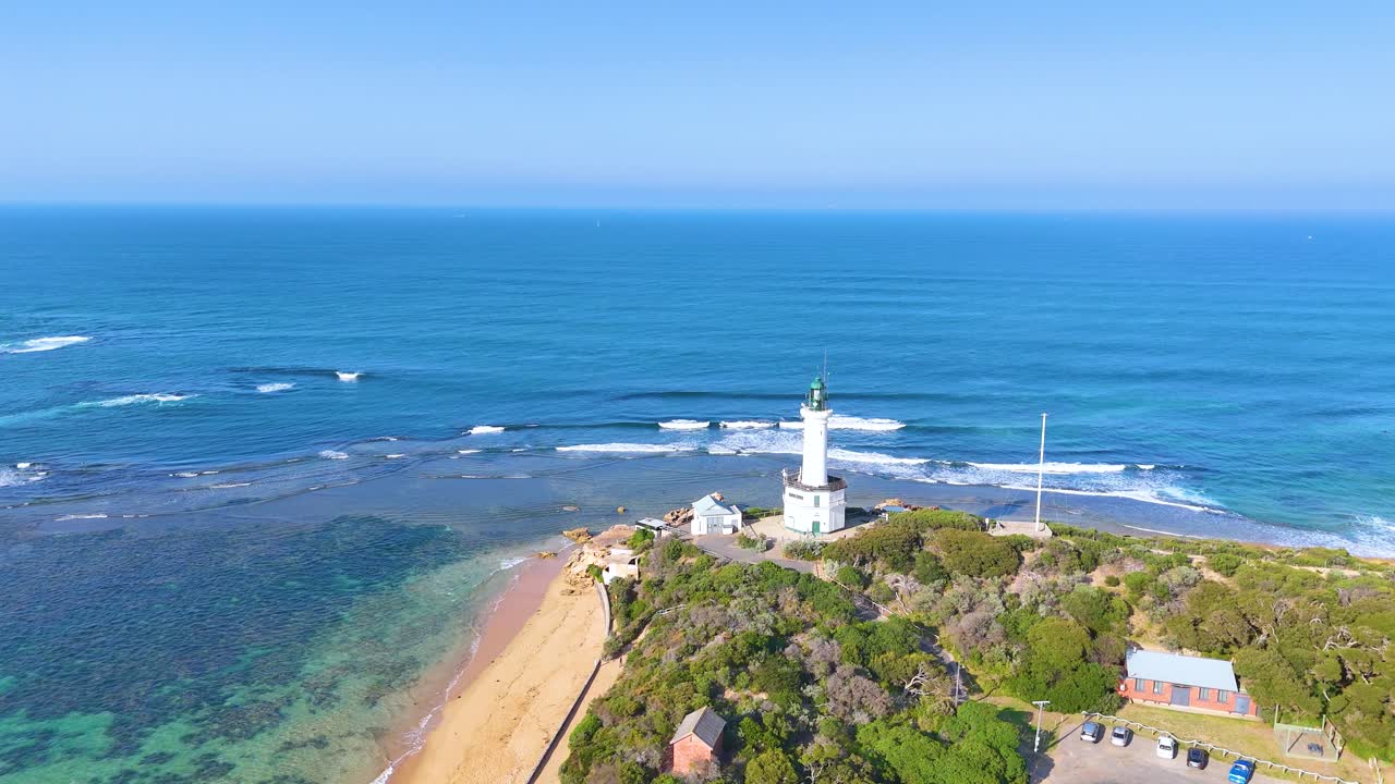 Aerial footage captures Point Lonsdale's lighthouse, beach, and ocean under clear skies, showcasing natural beauty and coastal architecture