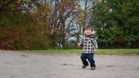 Alegre-Niño-Asiático-Saltando-Sobre-El-Césped,-Divertido-Paseo-Por-El-Parque