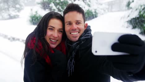 couple taking selfie on mobile phone during winter