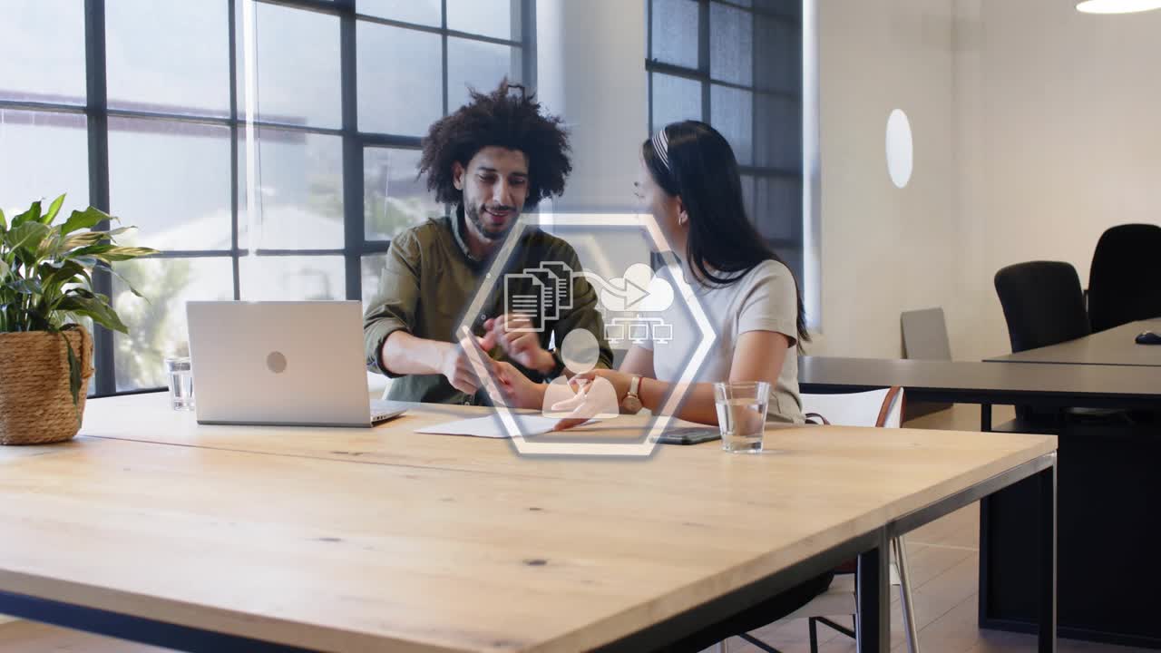 Man leaning in opening laptop, woman writing, tech hex graphics appearing, mapping CIFS NFC 24 or 7