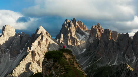 hombre con chaqueta roja parado solo en los dolomitas italianos