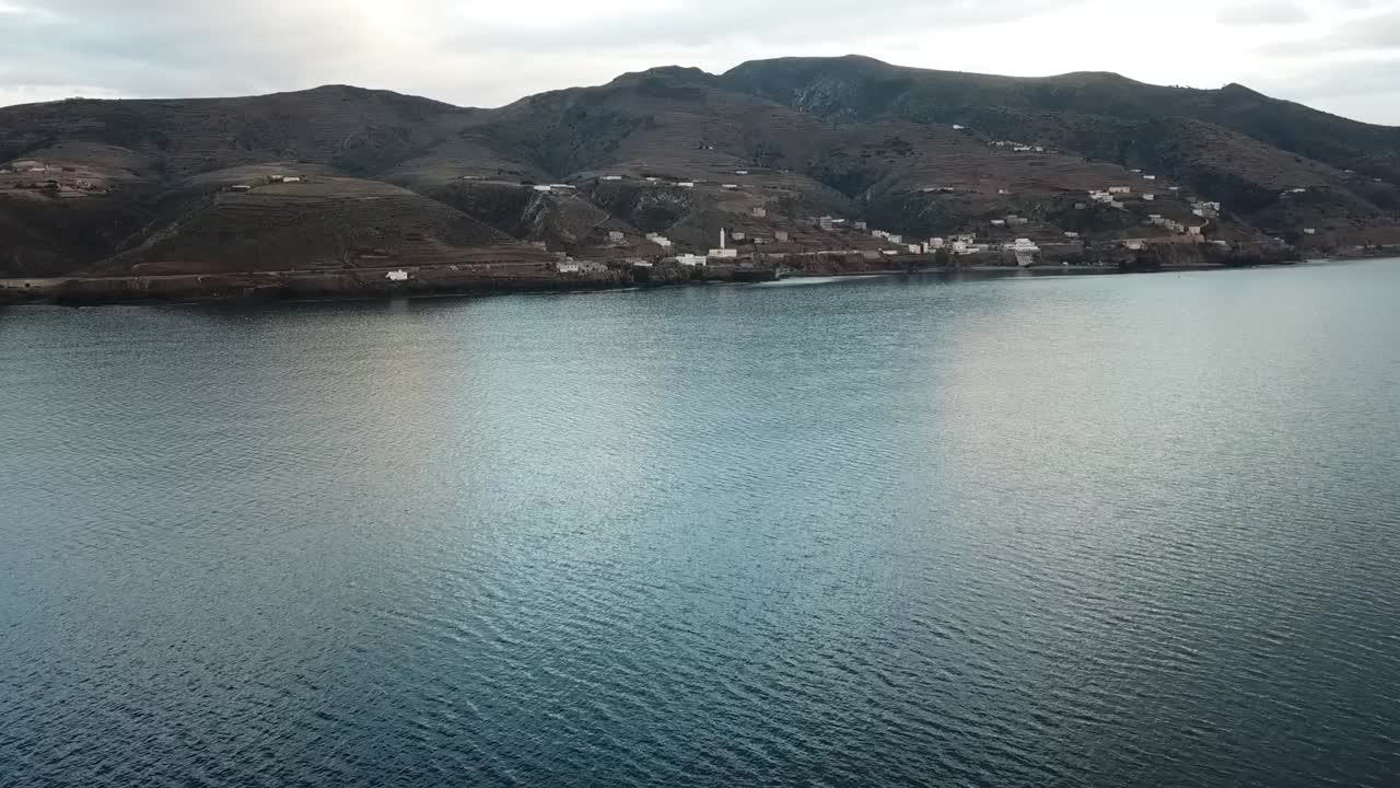 Wide seascape shot taken from the water looking towards the land. The silhouette of the distant coastline is visible on the Mediterranean horizon