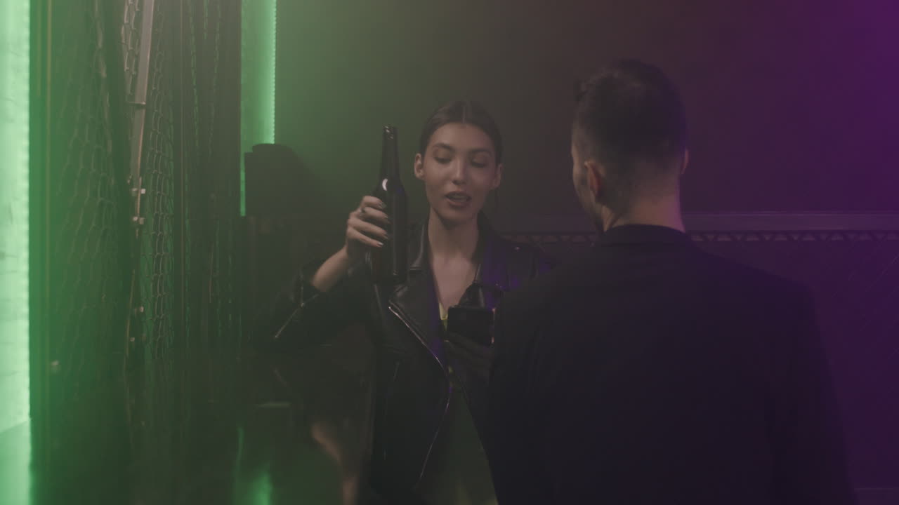 Beautiful Girl With Braces Holding Mobile Phone And Talking With Her Male Friend Sitting In Front Of Her At Disco