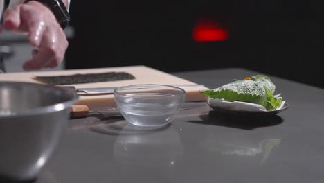 a static shot captures a sushi chef beginning to roll a fresh sushi roll, highlighting precision and technique. perfect for culinary, sushi preparation, and professional kitchen content.