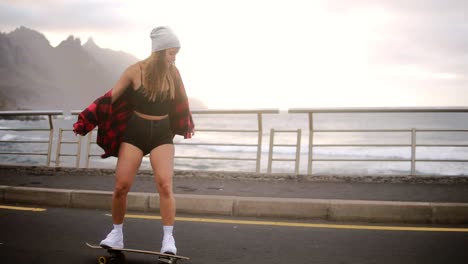Sport,-Lifestyle,-Extreme-And-People-Concept-Beautiful-Girl-Riding-Longboard-By-The-Coastline-Road-In-Cloudy-Weather