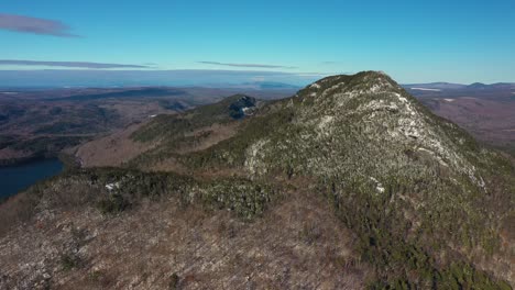 aerial orbit of a far off snow dusted mountain in maine