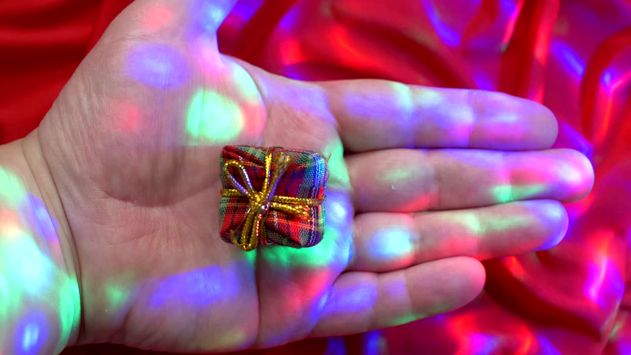 Mano caucasica che regge una piccola scatola regalo.