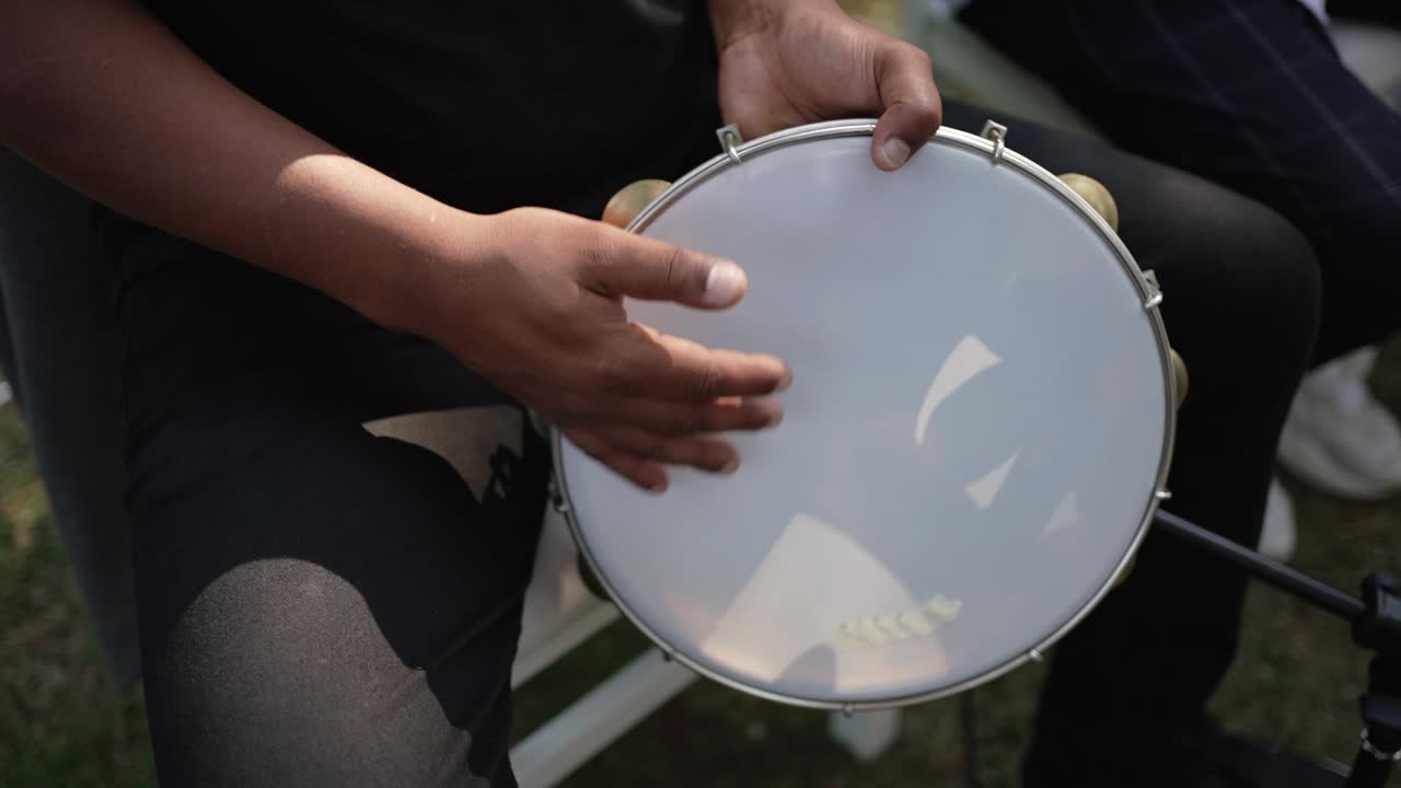 Close up of a musician playing a hand drum during an outdoor live performance