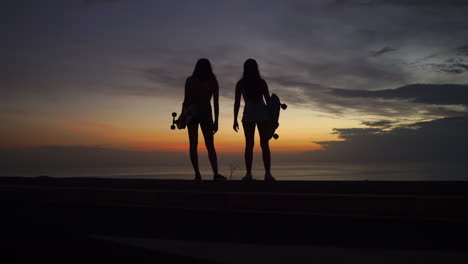 after skateboarding on the mountain's peak, girlfriends admire the stunning sunset sky view